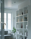 White bookcase with decorative items in a room with a window and sofa.