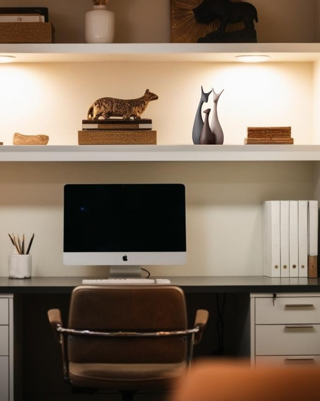 Animal-shaped decorative accents on white floating shelf and dark wood desk in farmhouse home office