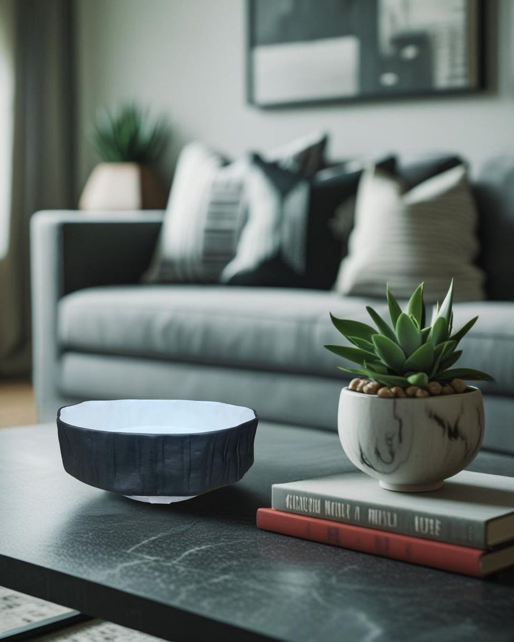 Black and white ceramic bowl on a black coffee table in a rustic-modern living room with striped cushions, a succulent plant, and neutral tones