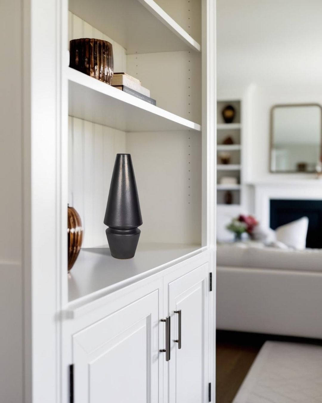 Black cone-shaped sculpture on light wood display shelf in farmhouse lving room