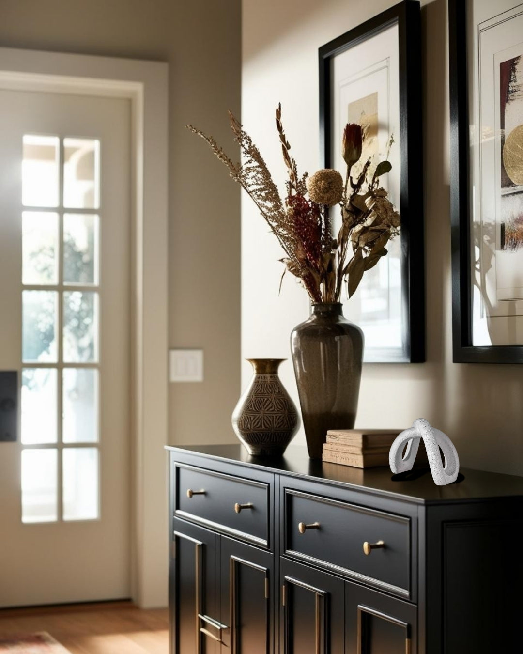 Decorative sculptural accent on black entry tale with mirror and vase in farmhouse entry