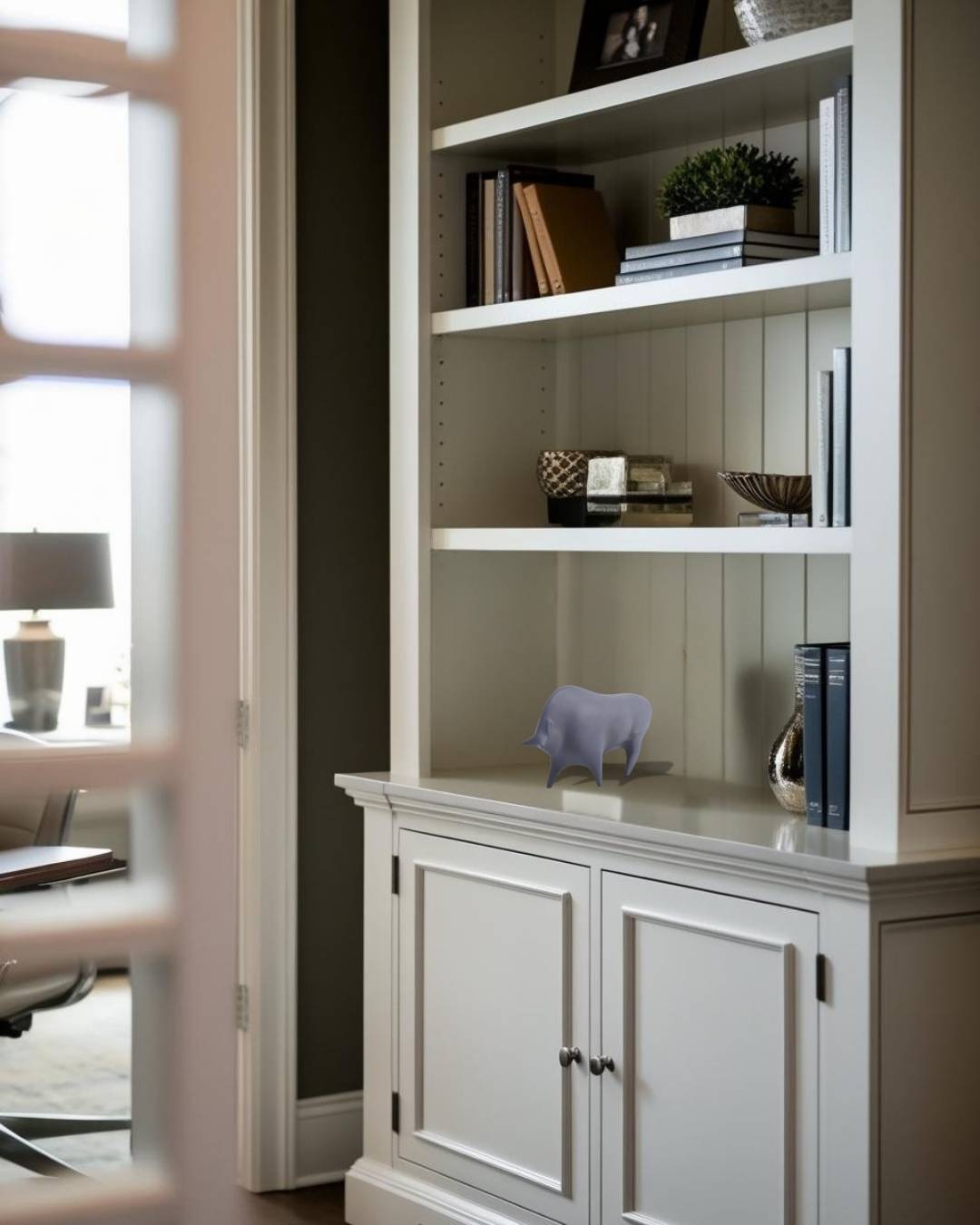 Gray concrete bull sculpture on white bookcase in a Japandi style home office