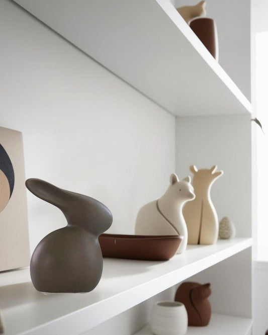 Modern ceramic animal-inspired decor on white shelf, featuring minimalist bunny, bear, and fox figurines in neutral tones for contemporary interior styling