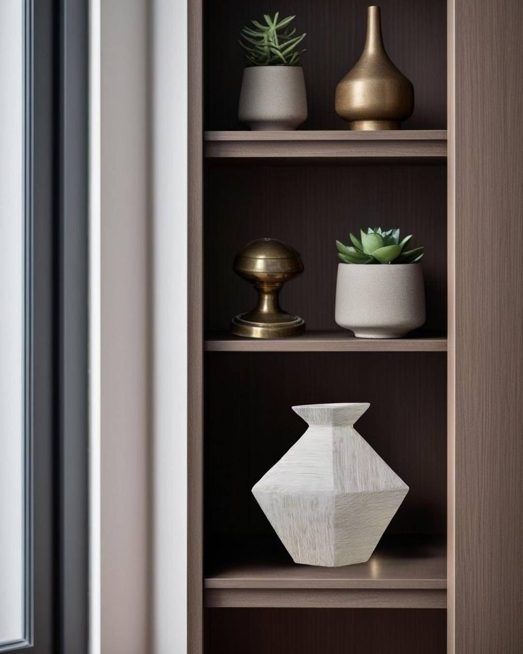Modern geometric greige ceramic vase on wooden shelf with minimalist home decor accessories.







