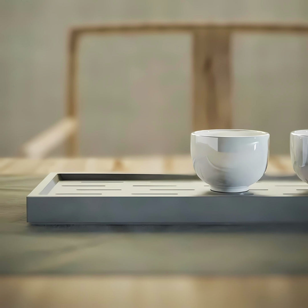 Modern nordic grey serving tray with white ceramic cups, set on a wooden table in a minimalist setting.