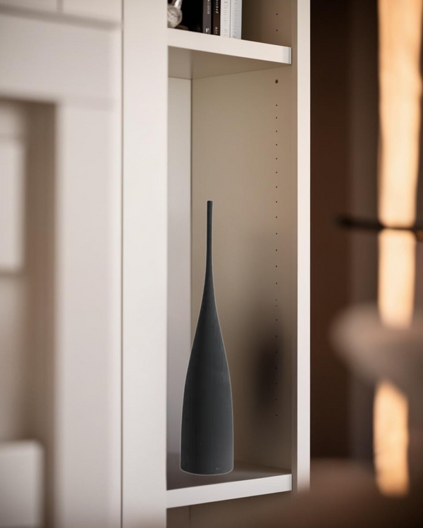 Tall black ceramic vase displayed on modern white shelf in minimalist home interior.