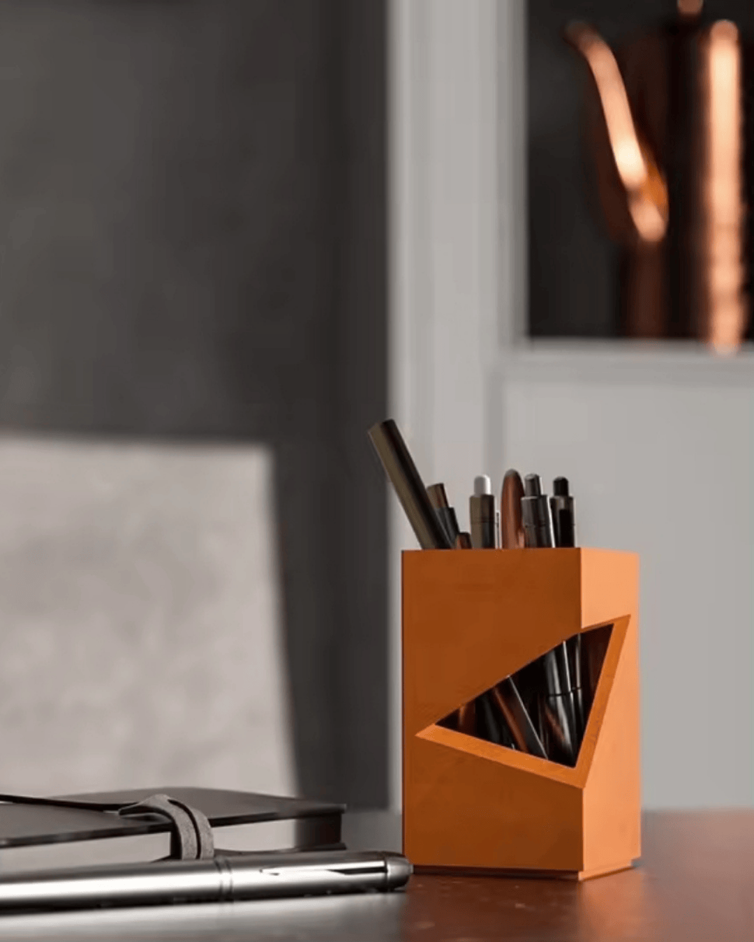 Modern orange pen holder on a desk in a rustic-modern home office with neutral tones and natural light