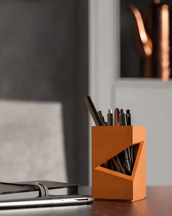 Modern orange pen holder on a desk in a rustic-modern home office with neutral tones and natural light
