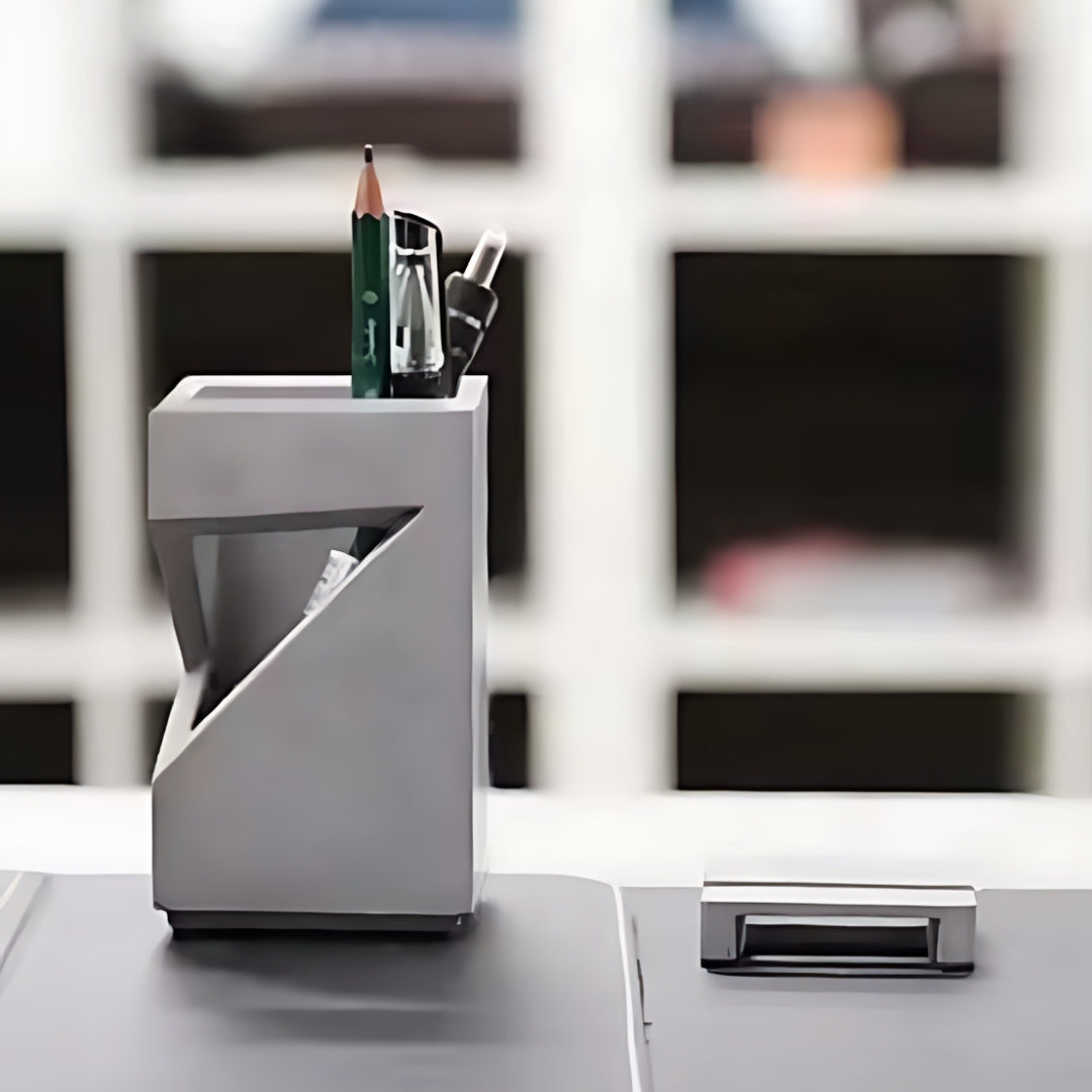 Nordic modern minimalist grey pen holder with a modern geometric design, holding several writing tools on a desk.