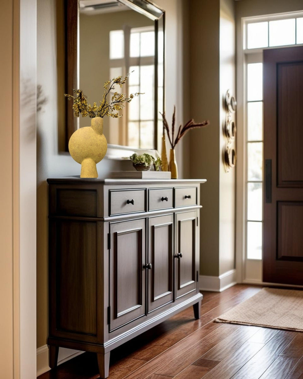 Ochre yellow sculptural vase on a dark wood entry table in the entry of a minimalist house