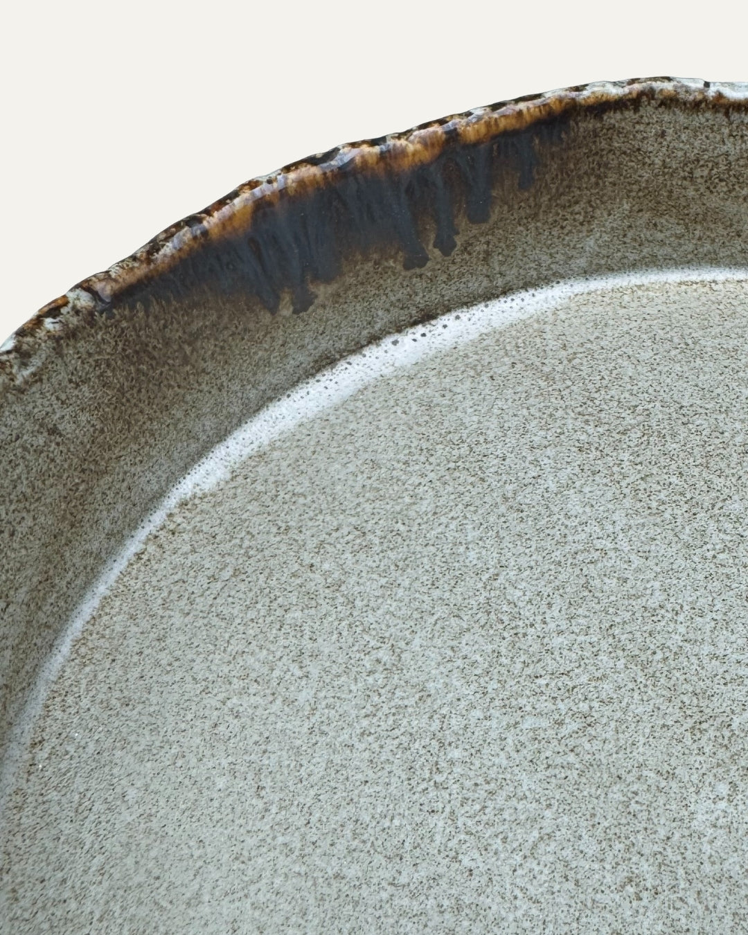 Detalle del interior gris moteado y del borde irregular oscuro del plato Rundebrett, visto de cerca.