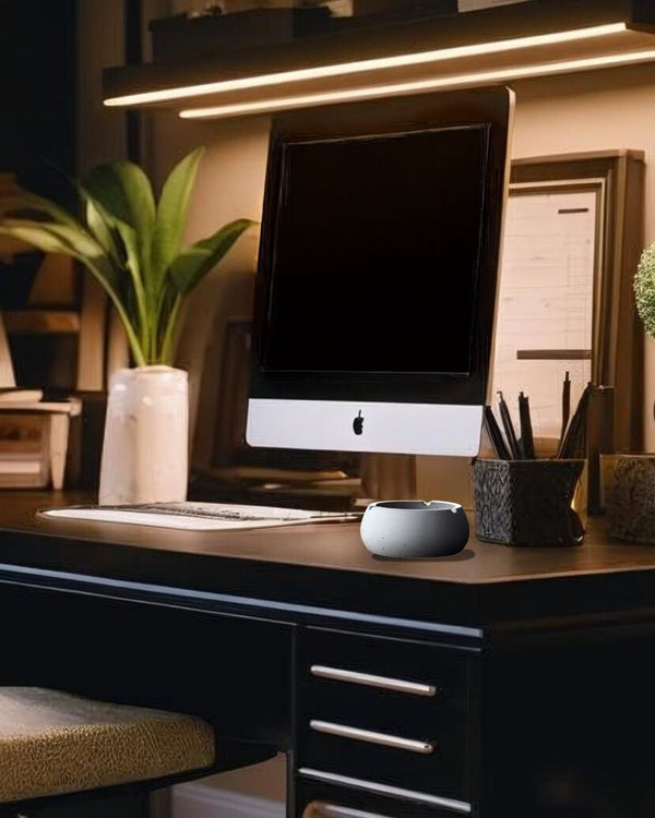 Preium gray concrete ashtray on a black desk in a rustic-modern home office with iMac and potted plants