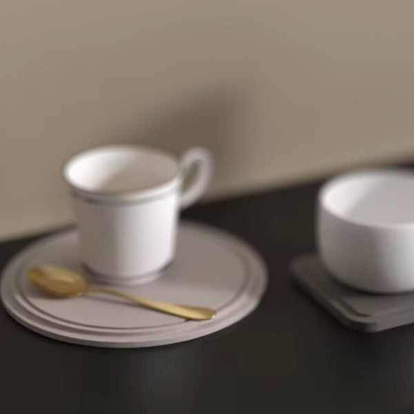 Round and square cup nordic holder trays with white cups and a gold spoon, set on a dark surface.