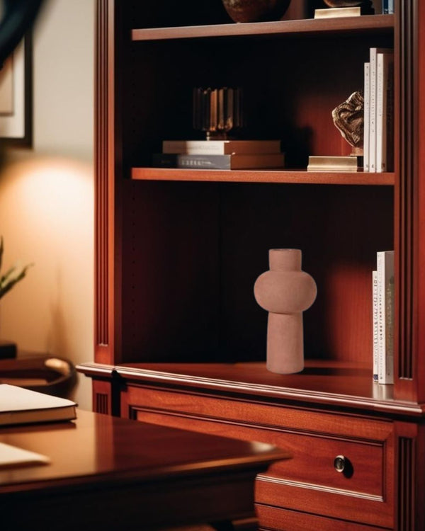 Sculptural terracotta vase on a dark wood shelf in a minimalist home office