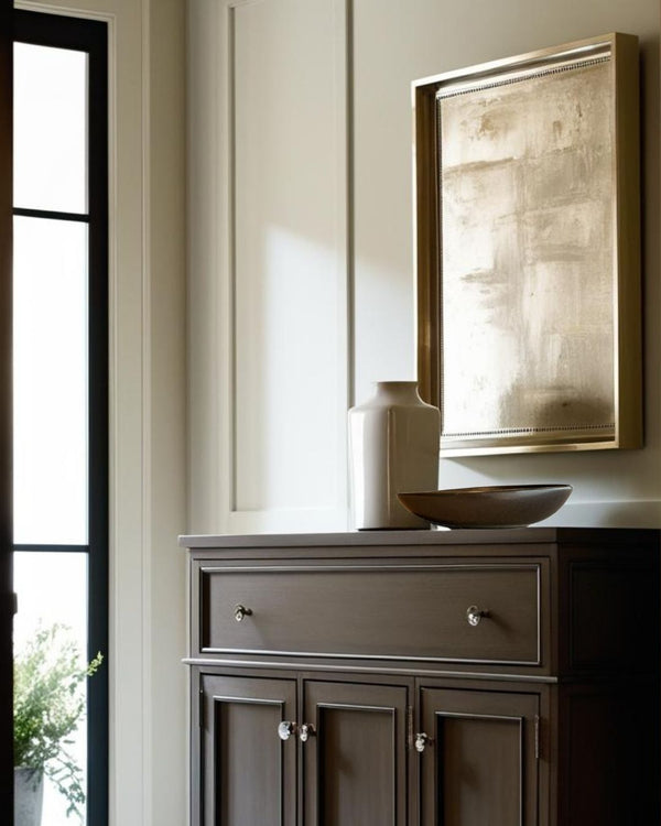 Shallow black sculptural porcelain bowl on a dark wood sideboard in an elegant farmhouse style entryway with neutral tones