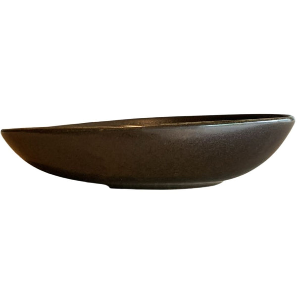 Side view of shallow black sculptural porcelain decorative bowl isolated on white background