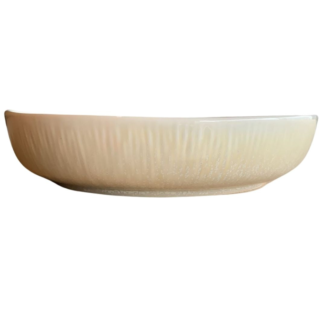 Shallow cream-colored rustic porcelain bowl side view on white background