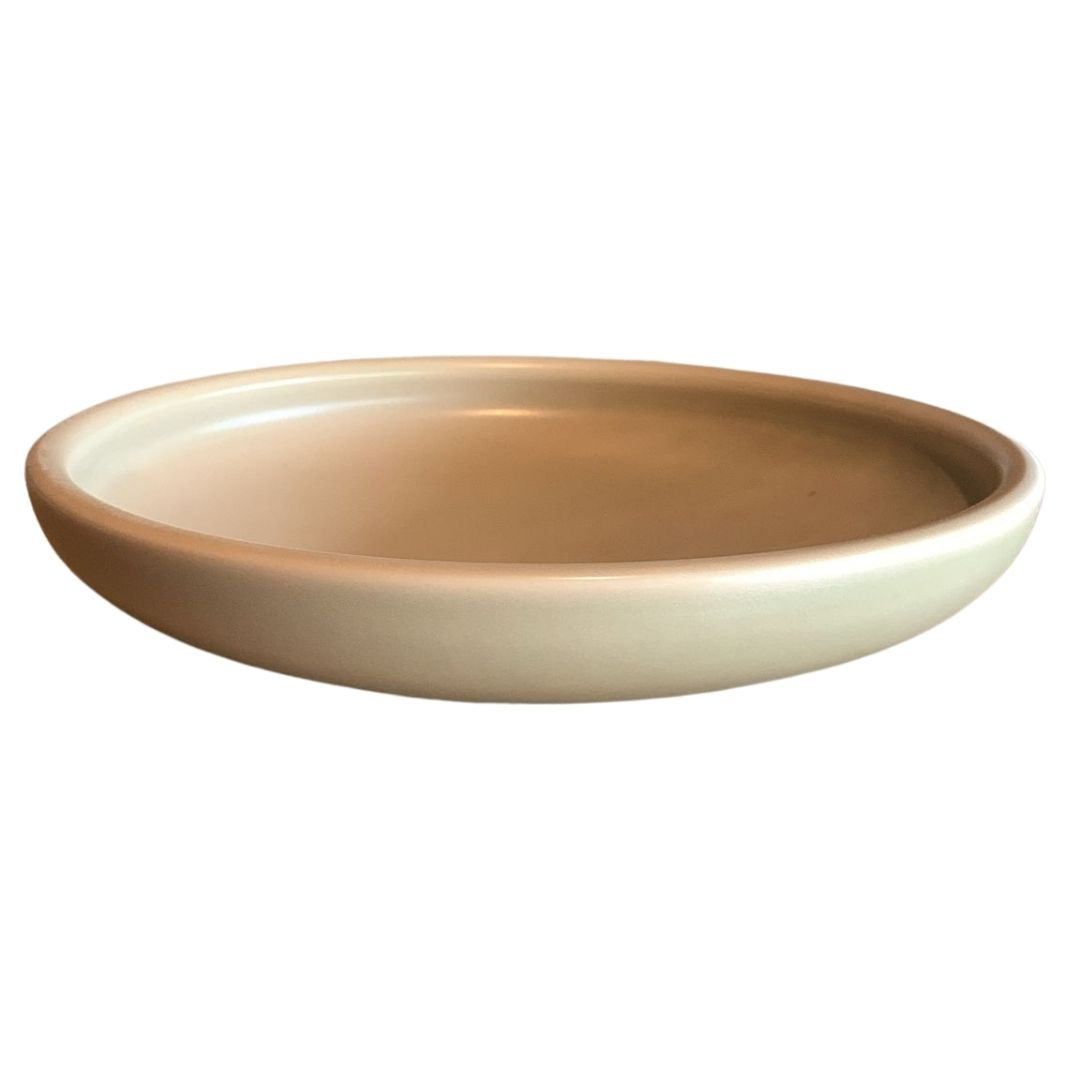 Top view of shallow porcelain bowl with beige outer surface and glazed interior, isolated on white background