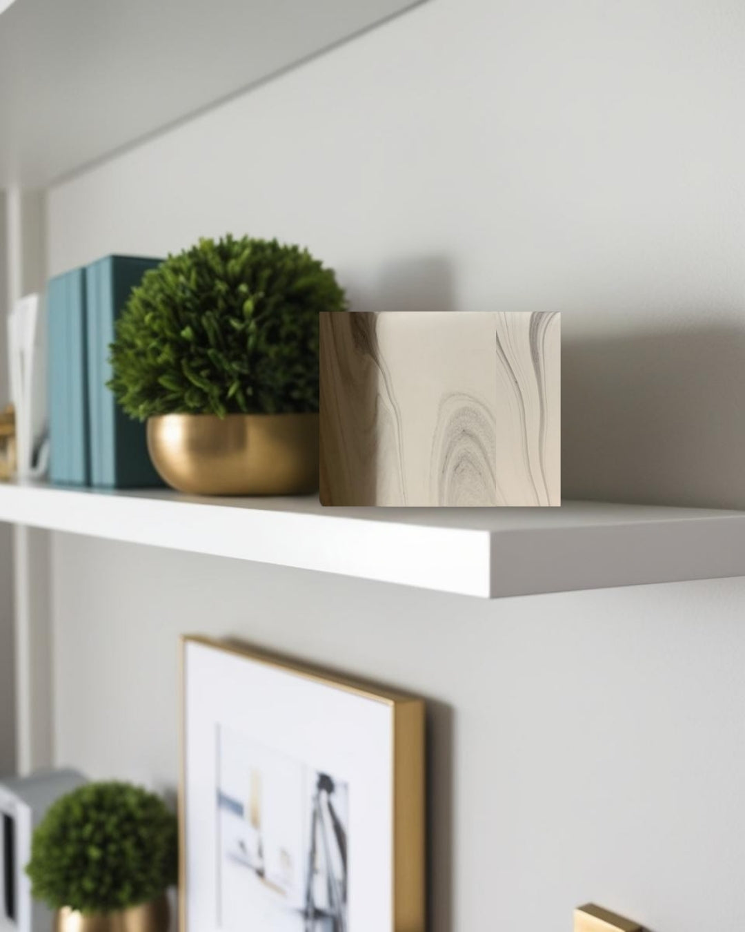 Square decorative accent on white floating shelf with small plant in farmhouse interior