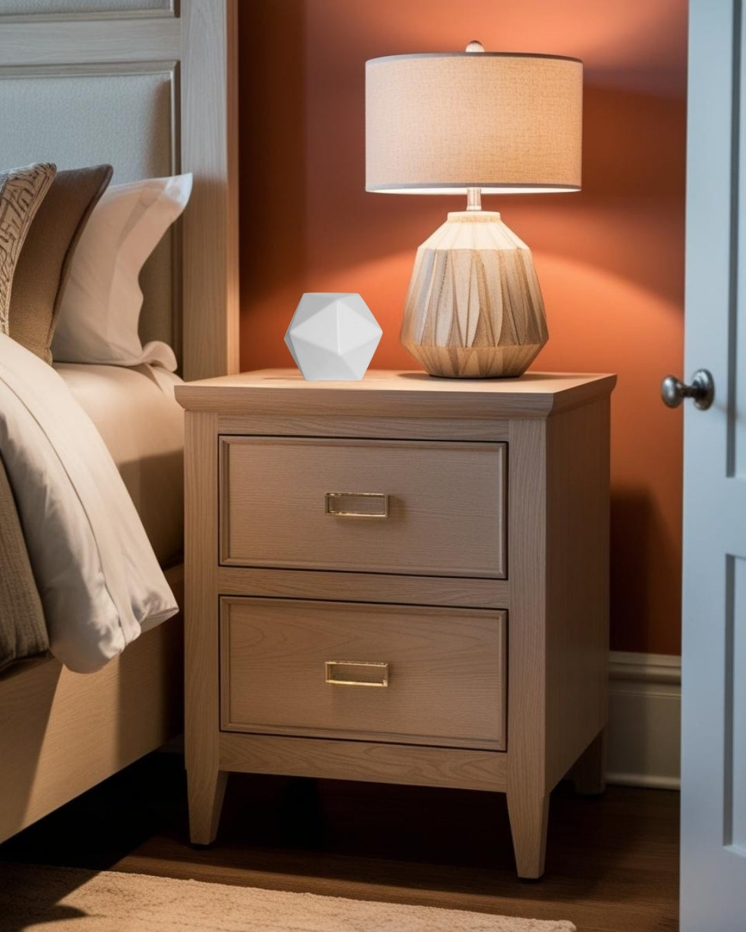 Geometric decor on wooden nightstand with lamp in warm transitional style bedroom