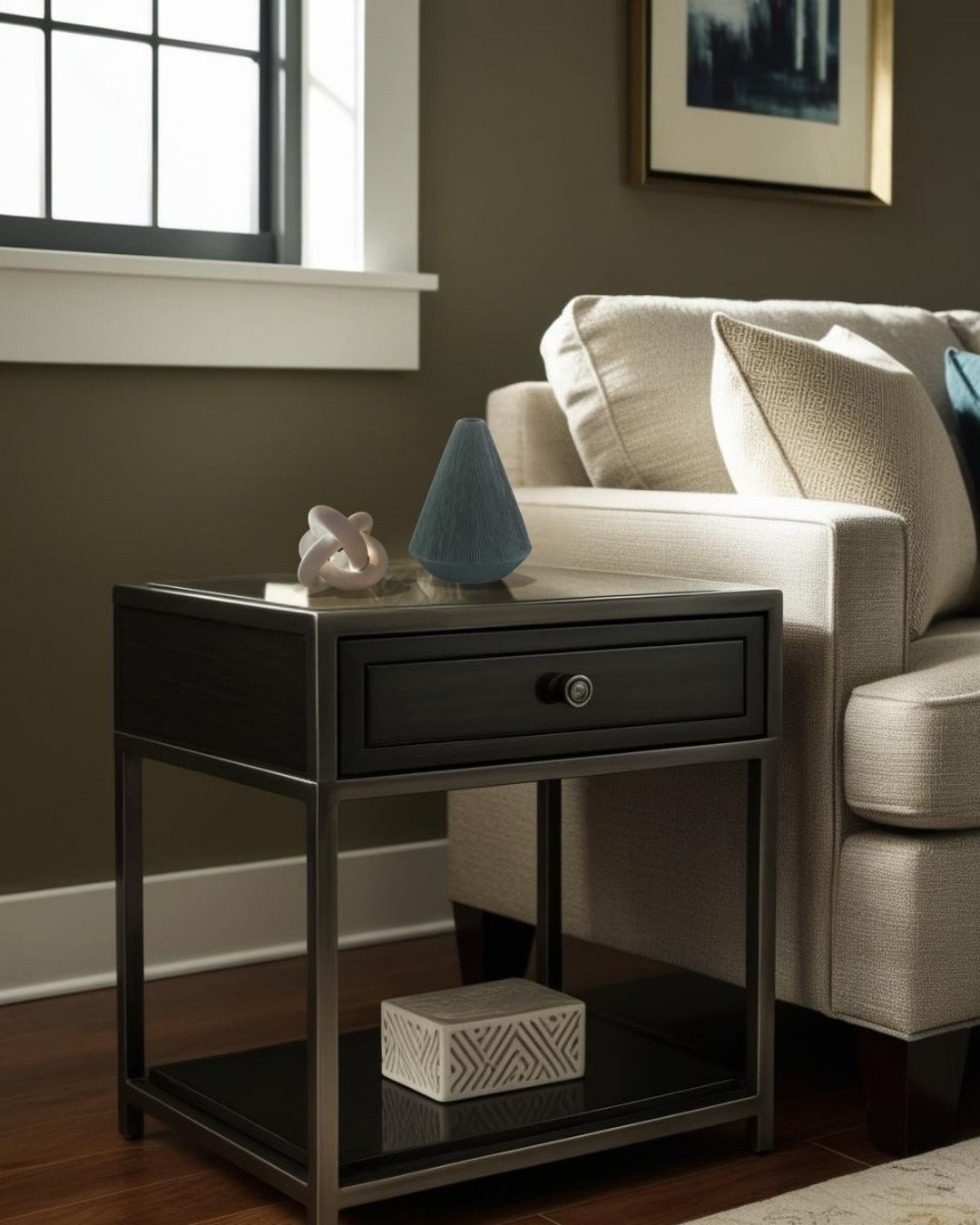 White geometric knot accent on black end table beside neutral farmhouse sofa in lving room