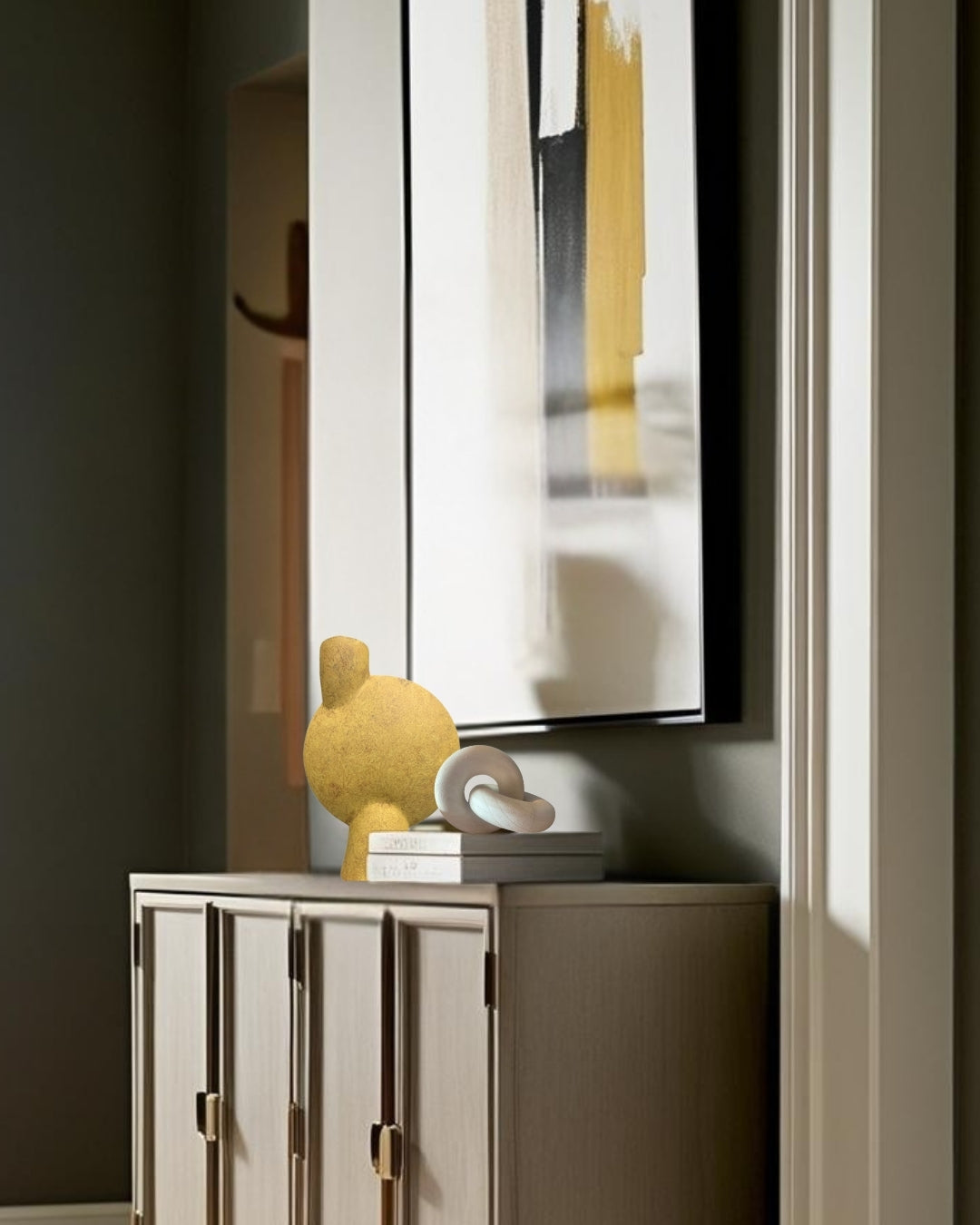 White geometric knot accent and yellow vase on wood entry table in transitional entry