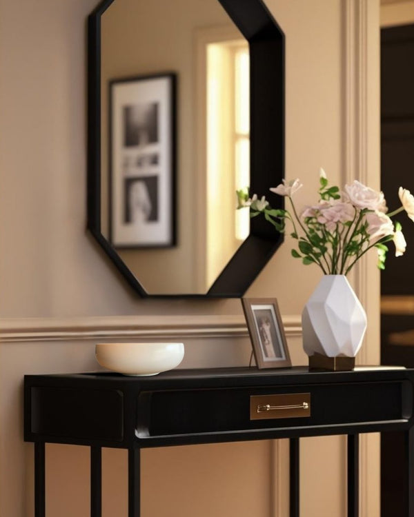 White shallow porcelain decorative bowl on a black entry table in an elegant farmhouse style entryway with mirror and floral vase
