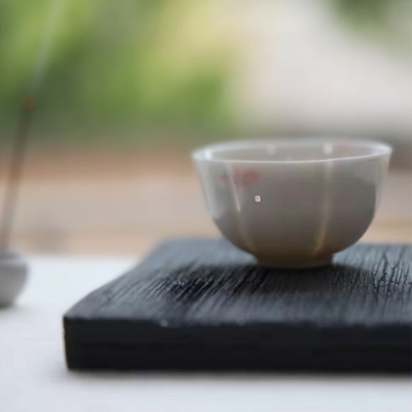 Wood-textured concrete nordic minimalist decorative tray with a small ceramic vase holding yellow flowers, placed on an outdoor surface.